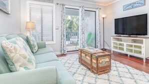 Una sala de estar con un sofá, un cofre de madera, un televisor y un letrero que dice "Tybee Island".