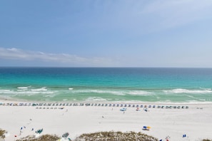 A beach with umbrellas and beach chairs, a lifeguard tower, and the ocean.