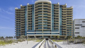 Un hotel de varios pisos con fachada curva, balcones en cada planta y vista al mar.