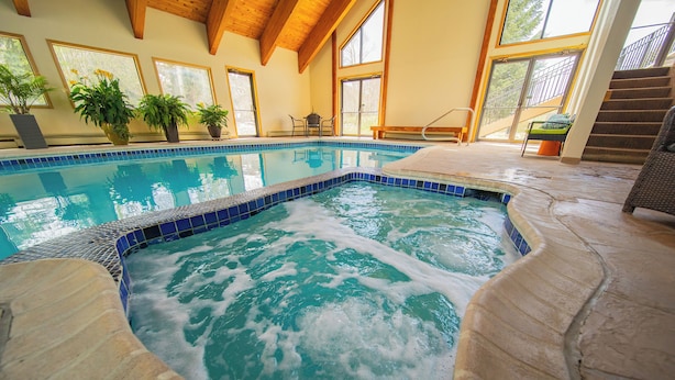 An indoor swimming pool with a stone deck, wooden beams, and potted plants. - Spacious Townhome Mountain View & Private Hot Tub (Keystone)