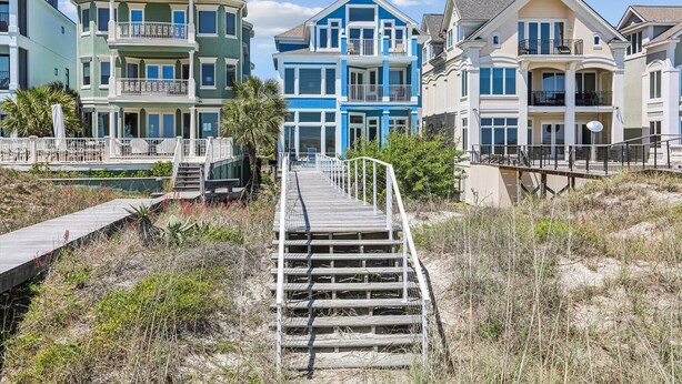 A coastal residential area with multi-story houses, a wooden staircase leading to a dock, and a sandy beach in the foreground. - 2 Collier, Oceanfront, Dogs OK, Pool, Free Golf, Elevator (Hilton Head)