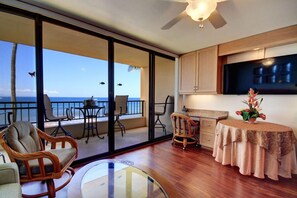 Enjoy a serene ocean view from the balcony, featuring a glass door and wicker chairs.