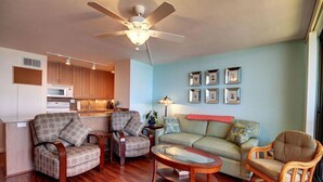 A living room with a sofa, two armchairs, a coffee table, and a ceiling fan. - Exquisite Renovated Beachfront Haven - Experience Sugar Beach #329 (Kihei)