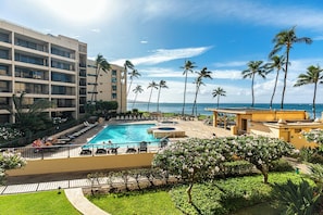 Ein Hotelpoolbereich mit Blick auf den Ozean, Palmen und ein Gebäude mit mehreren Balkonen.