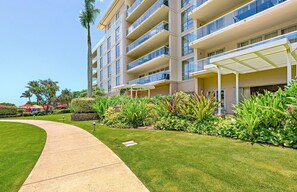 A multi-story hotel with a well-maintained lawn, outdoor seating area, and a clear view of the building's exterior.