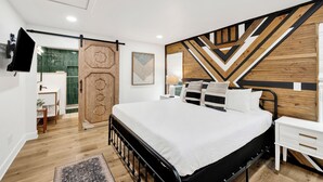 A modern bedroom with a bed, bedside table, and a geometric-patterned wall. - Gulf Front | Pet Friendly | Spacious Porch (Gulf Shores)