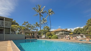 A swimming pool with clear blue water, surrounded by palm trees and lounge chairs. - Kihei Bay Surf #110 Studio Modern/Beach Decor, A/C, Across Beach Cute & Comfy (Kihei)