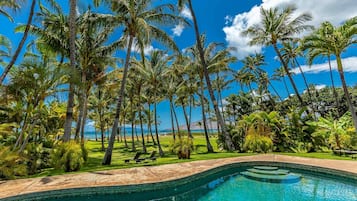 A swimming pool surrounded by palm trees and a clear blue sky.