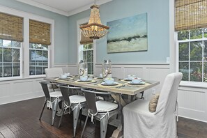 Une salle à manger avec une table en bois dressée pour six personnes, entourée de chaises.