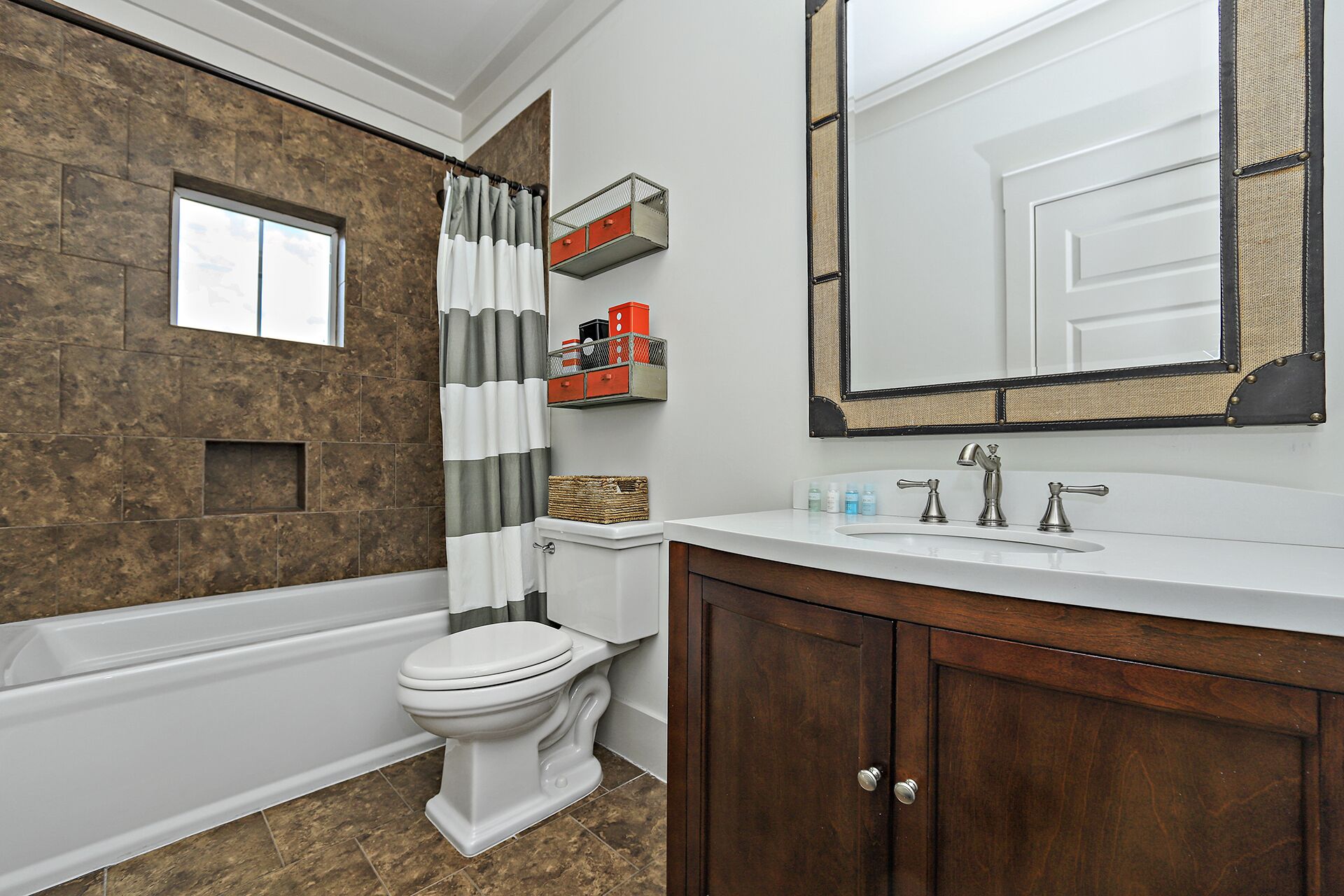 A bathroom with a bathtub, toilet, and vanity with a mirror.