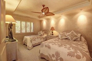 A bedroom with two beds, a ceiling fan, a nightstand with a lamp, and a statue on a side table.