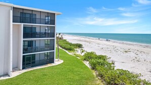 A modern multi-story building with balconies overlooking a beach.