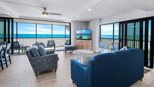 A spacious balcony with a view of the ocean, furnished with a blue sofa, a patterned sofa, and a small table.
