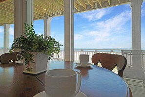 Enjoy a meal with a view of the ocean from this dining area, featuring a table set with a cup, saucer, and potted plant.