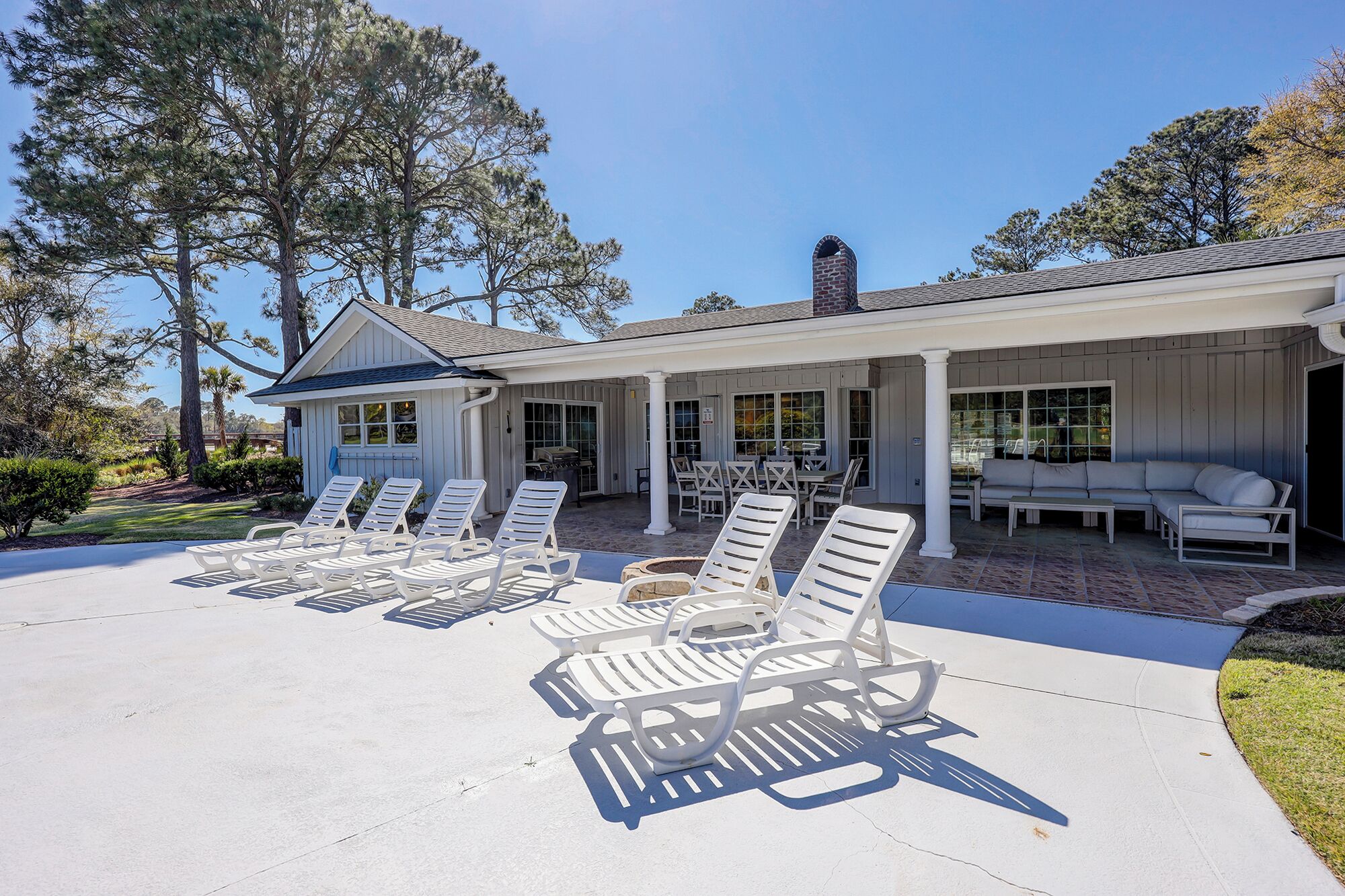 A house with a covered patio area featuring sun loungers and a dining table.