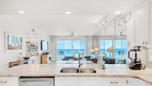 Una cocina moderna con una isla grande, lavavajillas integrado y vistas al océano a través de amplios ventanales.