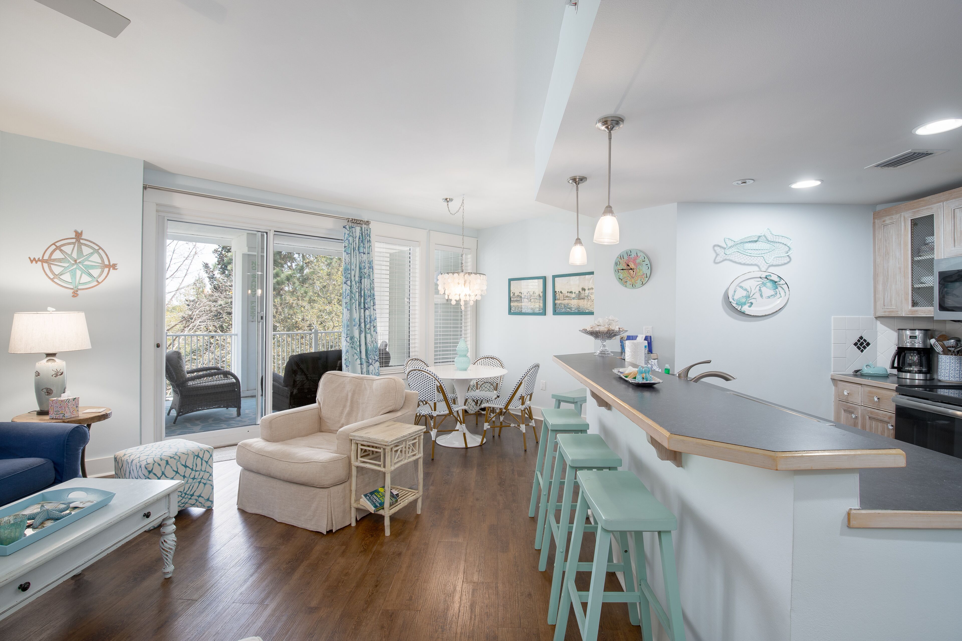 A modern kitchen with a bar area, dining set, and a view to the outside.