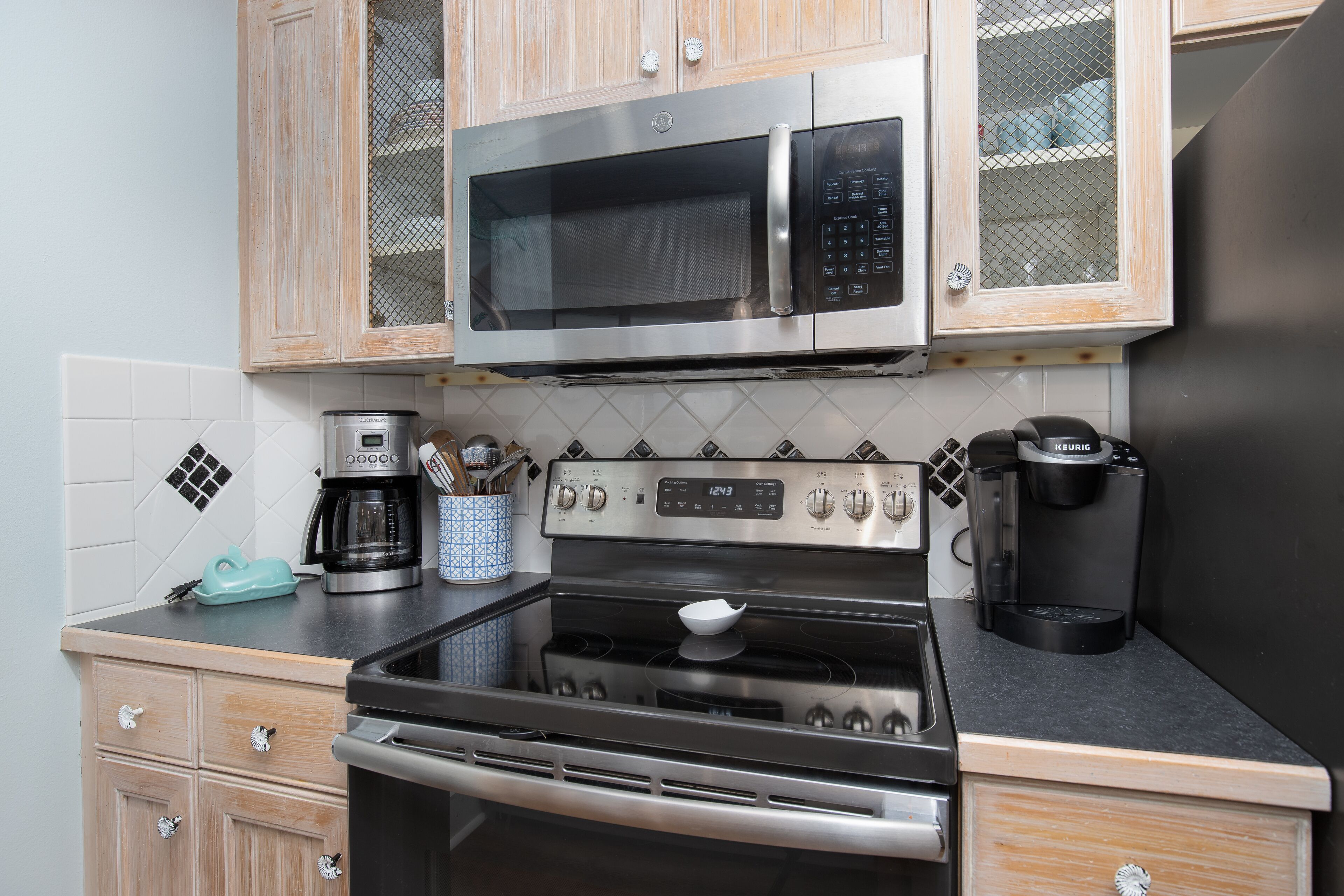 A kitchen with a stainless steel microwave, stove, and coffee maker.