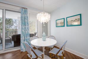 Un coin repas avec une table ronde, quatre chaises, un lustre et deux tableaux encadrés accrochés au mur.