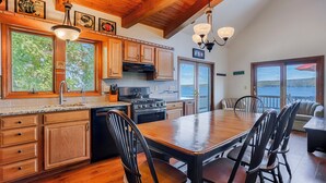 Une cuisine avec des meubles de rangement en bois, une cuisinière et un coin repas comprenant une table et des chaises.