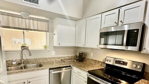 A kitchen with white cabinets, a stainless steel dishwasher, a microwave, and a stove. - Beach Getaway! Pet-friendly! Chateau La Mer 15E! (Destin)