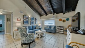 A spacious living room with a high ceiling, a sofa set, a coffee table, and a television. - Beach Getaway! Pet-friendly! Chateau La Mer 15E! (Destin)