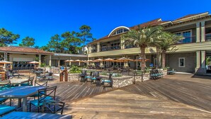 An outdoor patio area with wooden tables and chairs, umbrellas, and a pool. - 913 Cutter Ct- Short Stays All Summer - Steps to Harbour Town and Marina (Hilton Head Island)