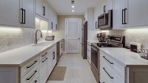 A modern kitchen with white cabinetry, stainless steel appliances, and a tiled backsplash. - 913 Cutter Ct- Short Stays All Summer - Steps to Harbour Town and Marina (Hilton Head Island)