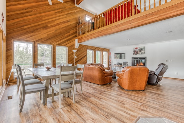 Enjoy meals in the central dining area surrounded by comfortable seating and a staircase leading to the upper level.