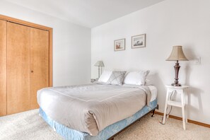 Cozy retreat with a large bed, nightstand, and framed artwork.