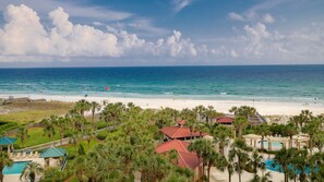 A beach resort with a pool area, palm trees, and a view of the ocean.