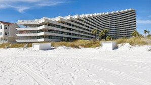 A modern hotel with multiple balconies and a beach view.