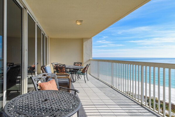 Varanda com vista para o oceano, mobiliada com mesa e cadeiras, e uma grade.