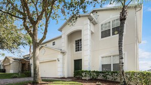 A two-story house with a garage, a covered porch, and a well-maintained lawn.