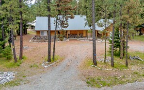 Une cabane avec une allée en gravier, entourée d’arbres.