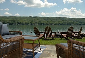 Eine Uferterrasse mit Korbmöbeln und einem Glastisch.