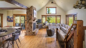 A spacious living area with a stone fireplace, a large sofa, and a dining table with chairs.