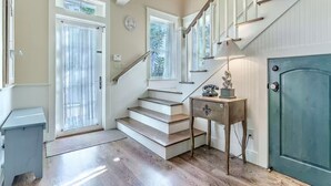 Una escalera de madera con barandilla que lleva a una puerta con un panel de vidrio.
