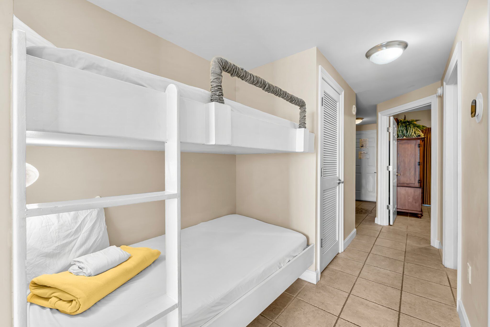 Habitación con literas, un colchón blanco y una toalla amarilla.