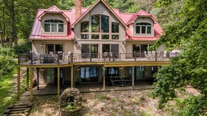 A large, two-story house with a balcony and a stone fireplace. - Dog Friendly Lakefront Home w/ Dock & Hot Tub (MCHENRY)
