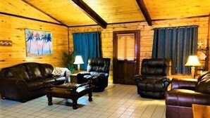 A cozy log cabin interior with a fireplace, leather sofas, and a tiled floor. - Beautiful 3 Bedroom, 2 Bath. Private Backyard. 321 Bayshore Dr. (Port Mansfield)