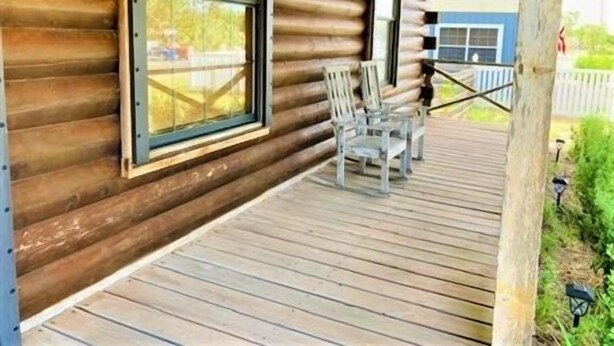A log cabin with a wooden deck and two chairs. - Beautiful 3 Bedroom, 2 Bath. Private Backyard. 321 Bayshore Dr. (Port Mansfield)