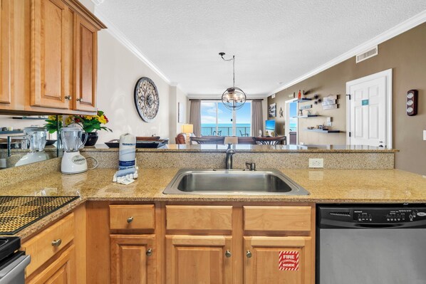 A kitchen with granite countertops, wooden cabinets, a stainless steel sink, and a dishwasher.