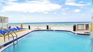 A pool with a view of the beach and ocean.