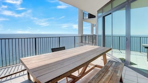 Uma mesa de madeira numa varanda com vista ampla para o oceano.