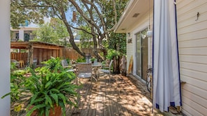 A wooden deck with outdoor furniture, surrounded by lush greenery and trees.