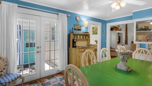A dining area with a green table, wooden chairs, and a decorative vase. - Close to Beach & Seaside, Vintage Cottage + Free Attraction Tickets! (Santa Rosa Beach)