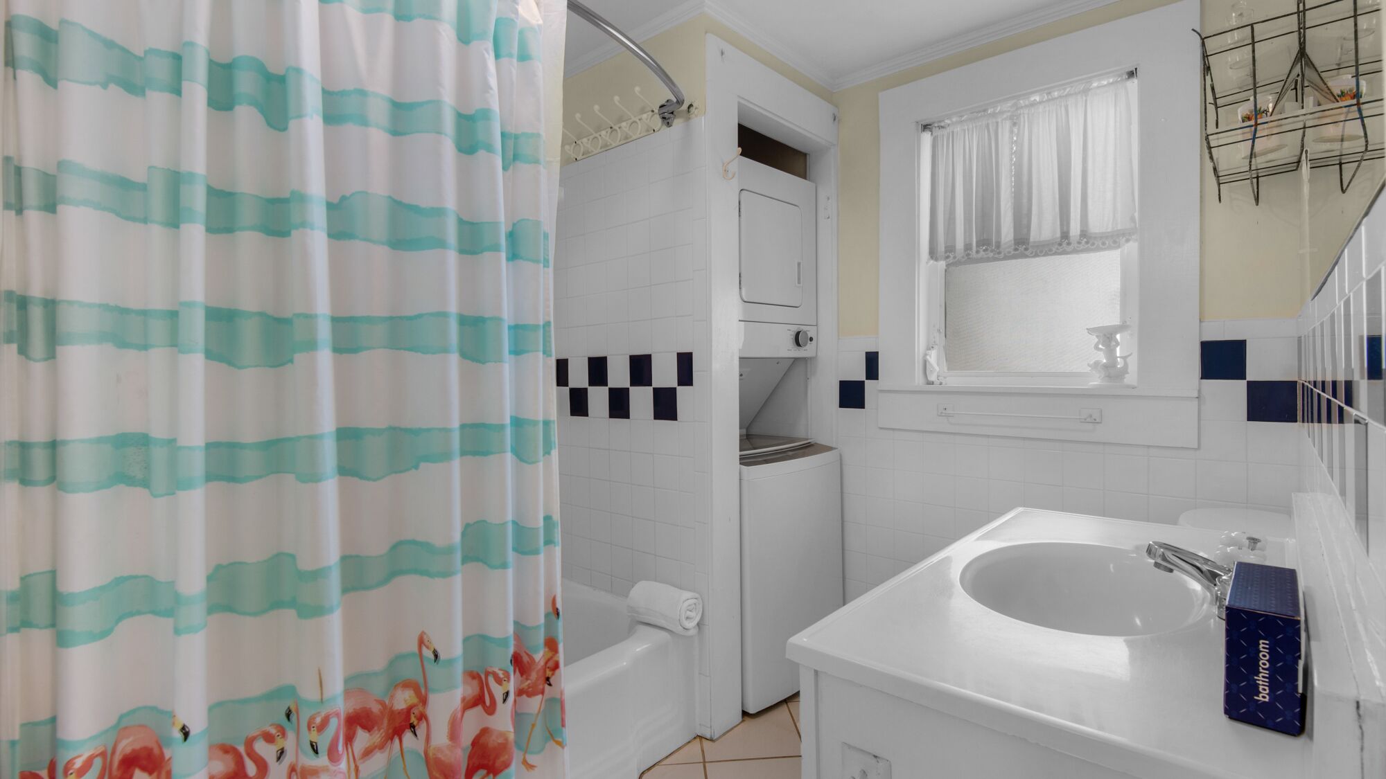 A bathroom with a shower curtain, a toilet, a sink, and a mirror.
