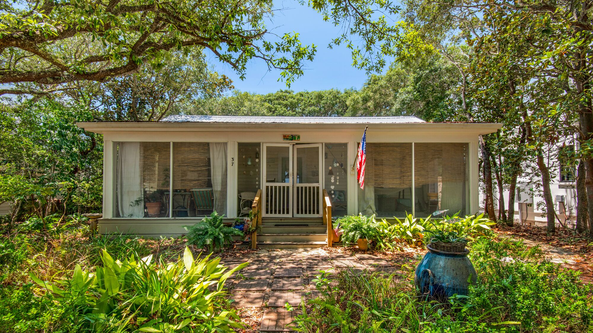 A small, single-story building with a porch, large windows, and an American flag.
