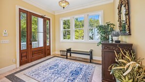 A hallway with a wooden door, a bench, a large window, and a decorative mirror. - 18 Sand Dollar, Oceanfront, Pool, Free Golf, Elevator, Great Views (Hilton Head Island)